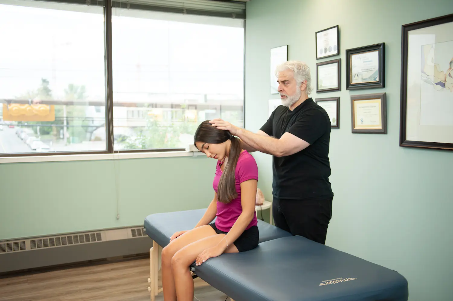 Therapist checking a client’s neck range of motion at Orthosports Calgary